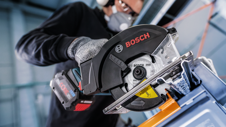 Object #200456726: 3088962_app_web_1 Person wearing safety equipment operates a cordless circular saw to cut metal.